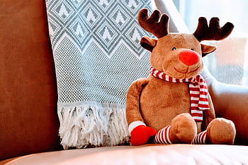 Adorable stuffed reindeer toy on a leather chair, creating a warm, festive atmosphere. HD wallpaper