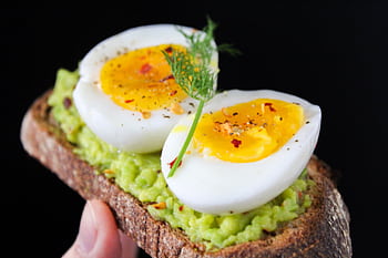 A delicious and healthy avocado toast topped with soft-boiled eggs, perfect for a nutritious breakfast. HD wallpaper