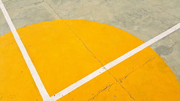 Close-up of a basketball court with yellow semicircle and white lines on concrete surface. HD wallpaper