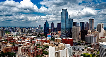A stunning panoramic view of the Dallas skyline under dramatic clouds, capturing the city's iconic skyscrapers. HD wallpaper