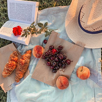 A que summer picnic featuring croissants, cherries, peaches, a hat, and an open book on a striped blanket. HD phone wallpaper