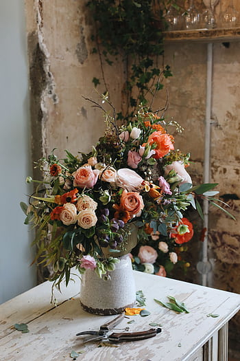 A beautiful bouquet of roses and mixed flowers on a rustic table indoors. HD phone wallpaper