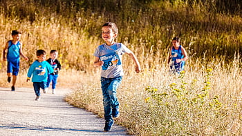 Children joyfully running in a park during a cheerful outdoor race event. HD wallpaper