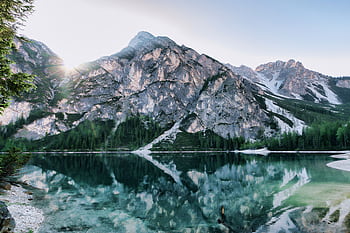 A breathtaking view of mountains reflecting on a serene alpine lake under a clear sky. HD wallpaper