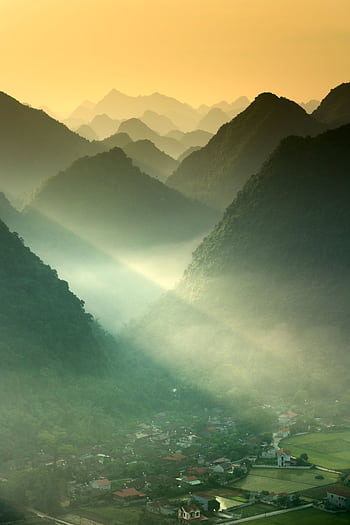 Stunning view of misty mountains and valley at sunrise, with sunrays highlighting the landscape. HD phone wallpaper