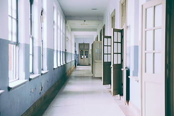A bright, empty hallway with open doors providing a clear perspective and ample daylight. HD wallpaper
