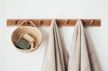 Minimalist bathroom setup featuring eco-friendly wooden hooks, towels, and basket with soap for a sustainable lifestyle. HD wallpaper