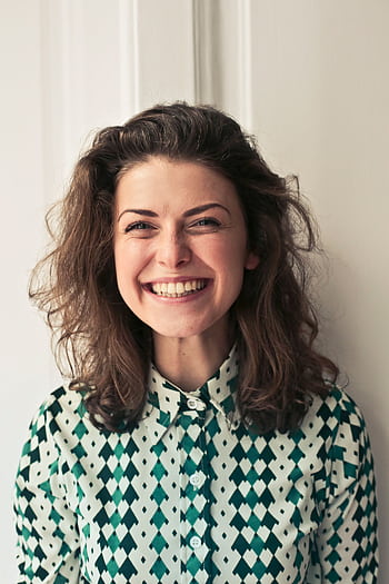 Portrait of a joyful brunette woman with a vibrant smile indoors, capturing happiness and positivity. HD phone wallpaper
