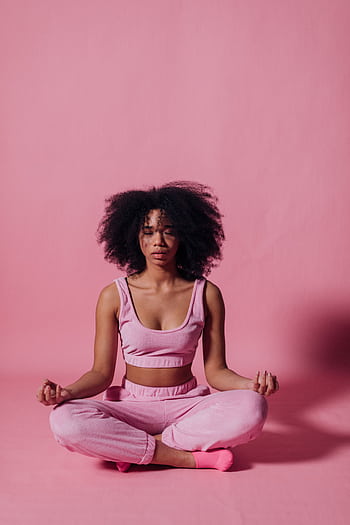 A woman meditating in yoga pose against a pink backdrop, embracing tranquility. HD phone wallpaper