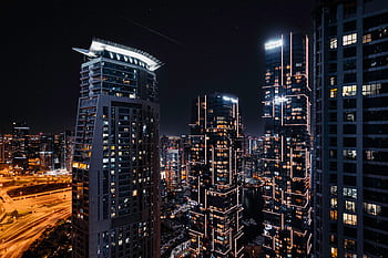 Stunning view of Dubai's modern skyline at night with illuminated skyscrapers and a bustling cityscape. HD wallpaper