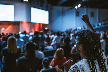 Vibrant crowd at a conference with a focus on an attentive participant. HD wallpaper