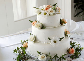 Elegant white wedding cake adorned with fresh roses and daisies, perfect for a romantic celebration. HD wallpaper