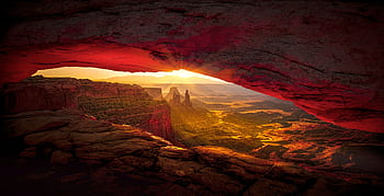 Captivating sunrise view through Mesa Arch in Canyonlands National Park showcasing vibrant desert landscape. HD wallpaper