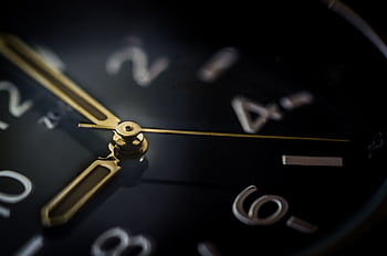 Detailed macro shot of an analog wristwatch showing gold hands and blurred numerals. HD wallpaper