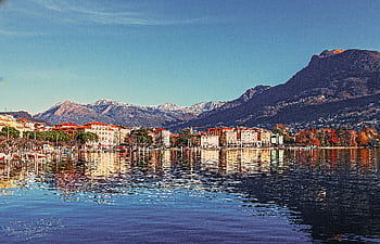 que coastal town with mountains reflecting in the tranquil lake waters. HD wallpaper