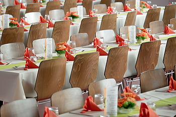 Beautifully arranged tables with wooden chairs for a formal event, adorned with orange flowers. HD wallpaper