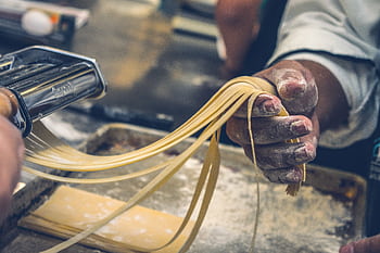 Close-up of hands making fresh pasta, showcasing artisanal techniques and ingredients. HD wallpaper