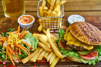 Delicious gourmet cheeseburger with crispy french fries and fresh salad on a wooden board. HD wallpaper