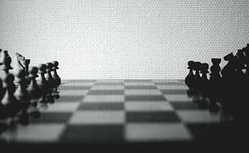 Black and white chess pieces set up on a board, highlighting strategic gameplay. HD wallpaper