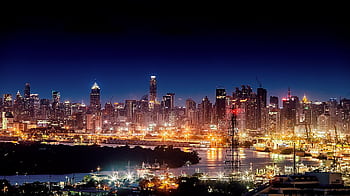 Stunning night cityscape showcasing illuminated skyscrapers and a lively urban skyline across a peaceful river. HD wallpaper