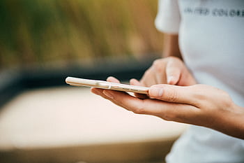 Close-up of a person using a smart outdoors, focusing on hands and device. HD wallpaper