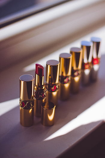 A stylish display of red lipsticks in gold tubes, capturing a chic and elegant look. HD phone wallpaper
