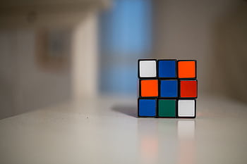 A close-up of a partially solved Rubik's Cube on a white table indoors. HD wallpaper