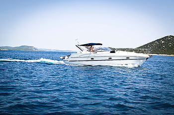 A sleek white yacht cuts through the open sea under a clear blue sky, capturing relaxation and travel. HD wallpaper