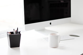 A minimalist work desk featuring a computer, coffee mug, and office supplies. HD wallpaper