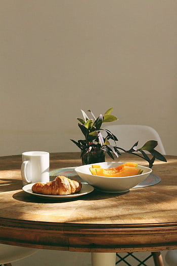 Cozy morning setup with a croissant, coffee, and fruit on a sunlit table. HD phone wallpaper