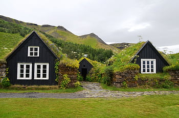 Explore the rustic charm of traditional turf roofed houses set against a lush hillside in serene countryside. HD wallpaper