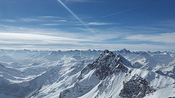 Stunning view of snow-covered mountain peaks under a clear blue sky in winter. HD wallpaper