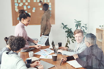 A diverse group of professionals discussing ideas in a modern office setting. Perfect for business and teamwork concepts. HD wallpaper