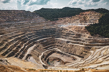 Aerial view of a large open-pit mine with terraced excavation during summer. HD wallpaper