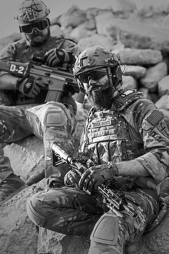 Two soldiers in tactical gear resting on rocky terrain, ready for action. HD phone wallpaper