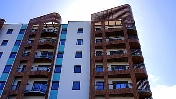 Explore the contemporary design and architecture of urban apartments with wooden accents and blue sky backdrop. HD wallpaper