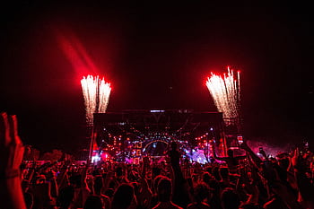 Thrilling concert scene with fireworks and vibrant crowd at night. HD wallpaper