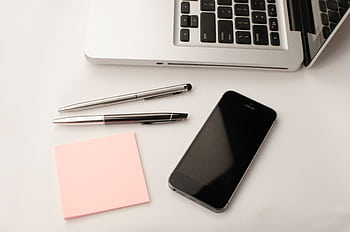 Clean and modern workspace featuring a laptop, smart, pens, and sticky notes. HD wallpaper