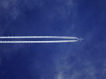 A jet airplane leaves contrails in a clear blue sky, symbolizing speed and modern aviation. HD wallpaper