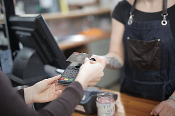 Close-up of customer and cashier during a credit card transaction at a store counter indoors. HD wallpaper