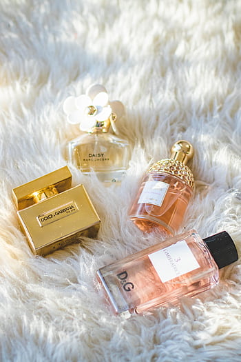 A collection of elegant perfume bottles arranged on a plush fur surface, showcasing luxury and sophistication. HD phone wallpaper