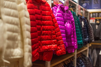 Vibrant winter jackets on display in a clothing store, showcasing a variety of colors for shoppers. HD wallpaper