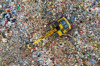 Aerial shot of a landfill with a yellow excavator in South Tangerang, Indonesia. HD wallpaper