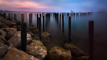 Seascape, sunset, wooden poles HD wallpaper