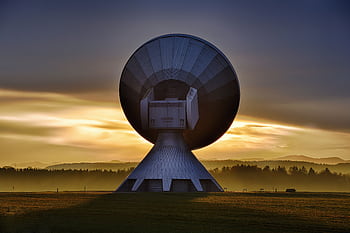 Large satellite dish silhouette against a colorful sunset, showcasing broadcasting technology. HD wallpaper