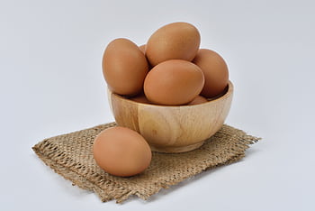 High resolution of brown eggs in a wooden bowl placed on burlap fabric, ideal for food-themed content. HD wallpaper
