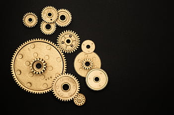 Close-up of gold gears arranged on a black backdrop, symbolizing teamwork and technology. HD wallpaper