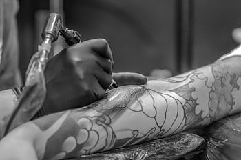 Artistic black and white capturing the detailed process of tattooing an arm. HD wallpaper