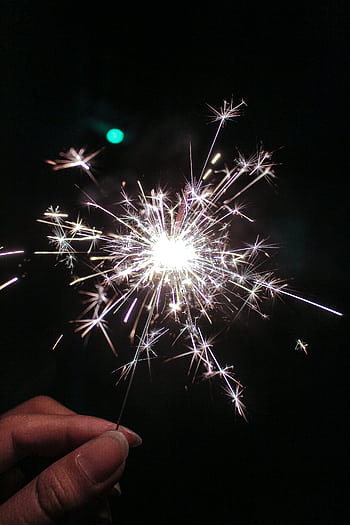 A bright sparkler held at night, celebrating festive occasions. HD phone wallpaper