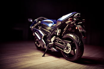 Artistic close-up of a blue sports motorcycle indoors, dramatic lighting accentuates its sleek design. HD wallpaper